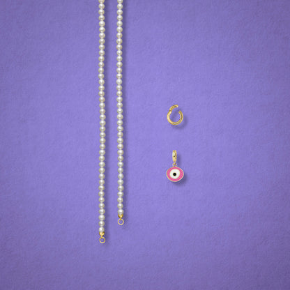 Blush Organic Evil Eye Charm, Golden Link Charm Holder, and the Lustrous Pearl necklace displayed separately on a lilac background to show styling options.