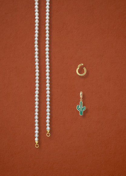 Separated components of the Lustrous Pearl Desert Bloom Charm Necklace, including pearl necklace, charm holder, and desert bloom charm in 14K solid gold by whywhy NYC.