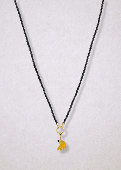Noir Elegance Banana Bliss Charm Necklace in full view, showcasing faceted black spinel beads, a golden link charm holder, and banana bliss charm with yellow enamel by whywhy NYC.