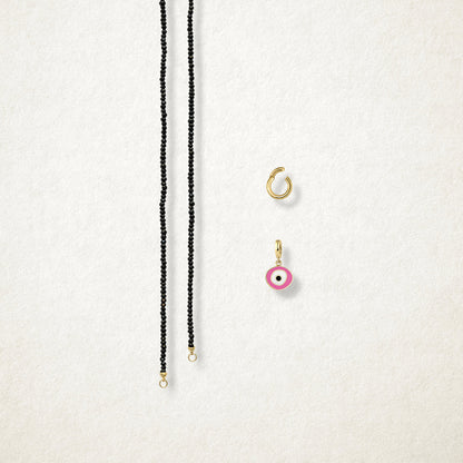 Blush Organic Evil Eye Charm and the Noir Elegance black spinel necklace displayed separately on a soft light background to show styling options.
