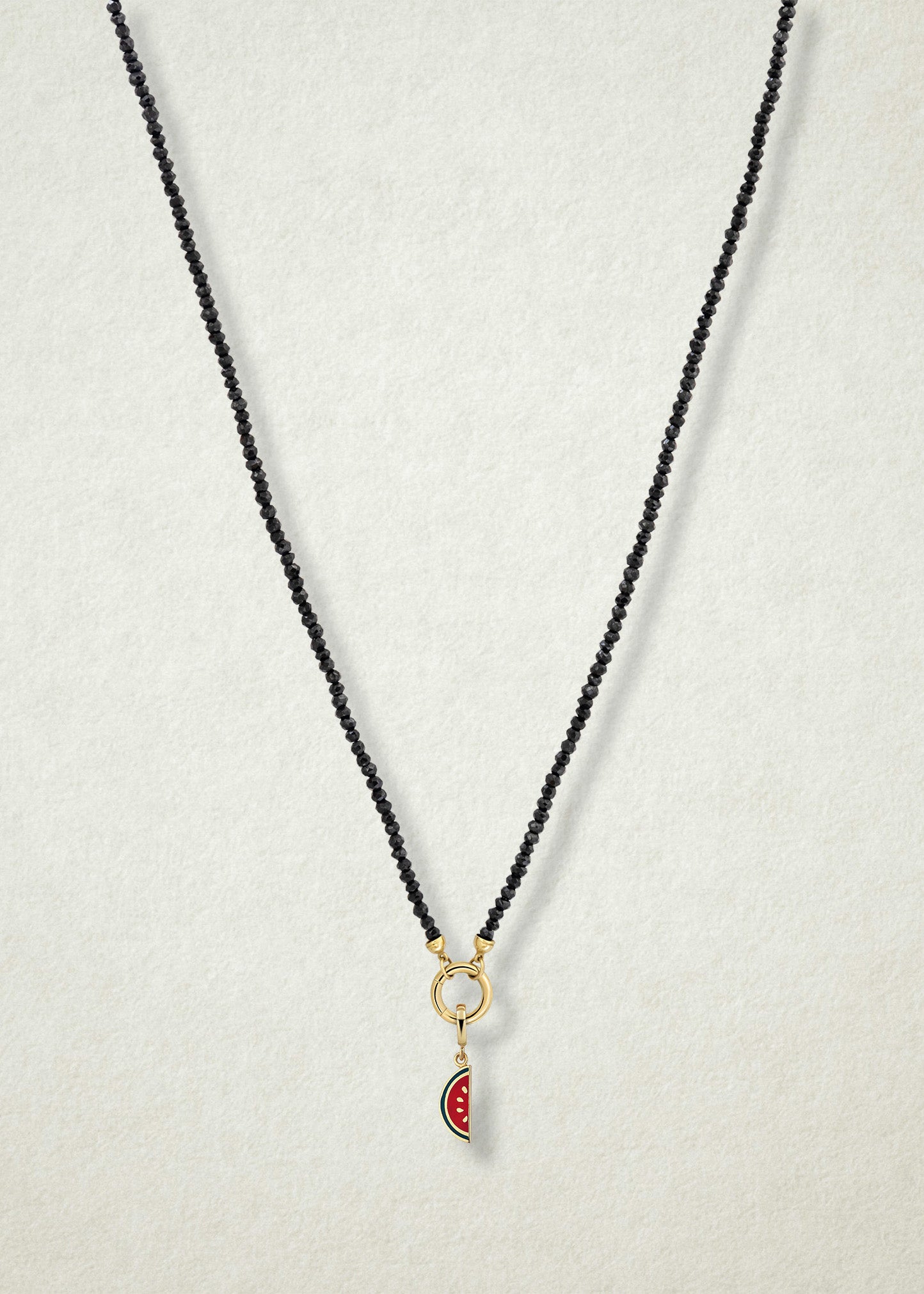 Noir Elegance Watermelon Wonder Charm Necklace in full view, showcasing faceted black spinel beads, a golden link charm holder, and watermelon wonder charm with pink and green enamel by whywhy NYC.