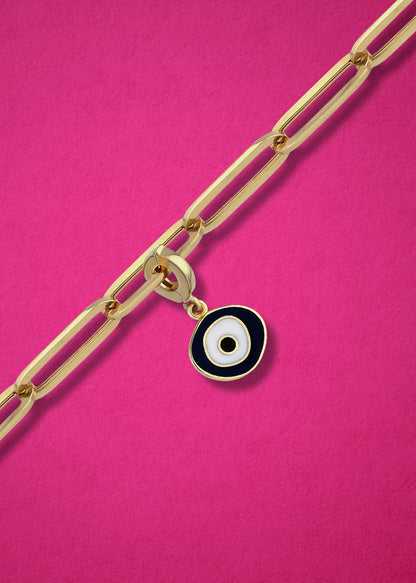Obsidian Organic Evil Eye clip-on charm crafted in 14K solid gold with black and white enamel, shown hanging on a gold chain on a magenta background.